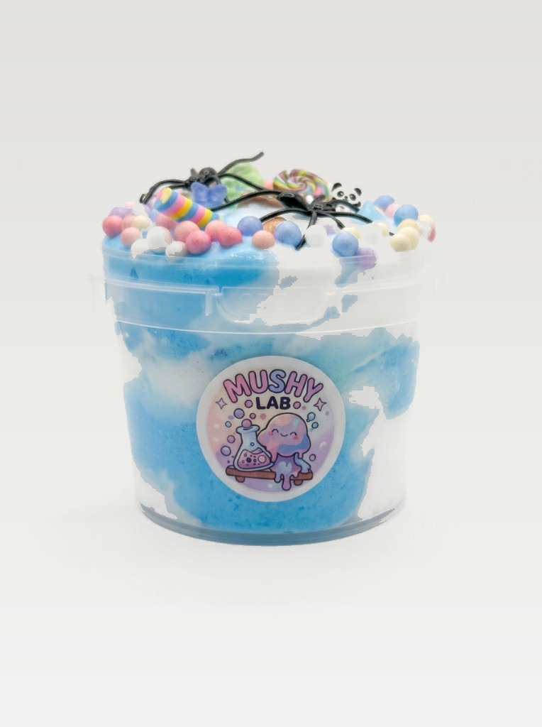 Blue and white Mushy Lab slime in a clear tub, topped with foam beads, candy, and charms